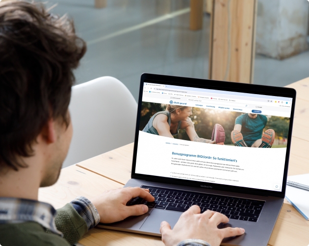 Ein Mann sitzt an einem Laptop, auf diesem sieht man die Website eines Kunden.